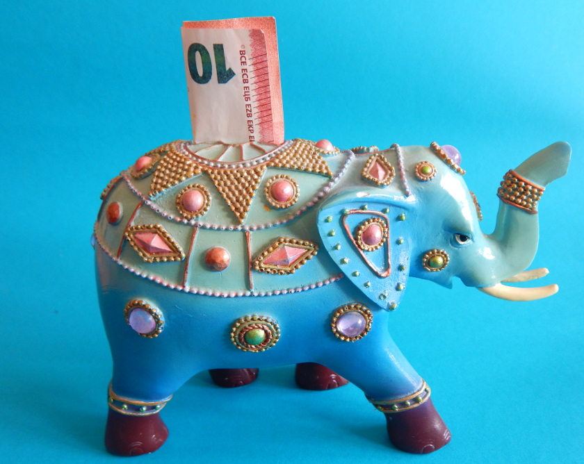 Geld sparen Urlaub. Spardose in Form eines Elefanten mit Geldschein